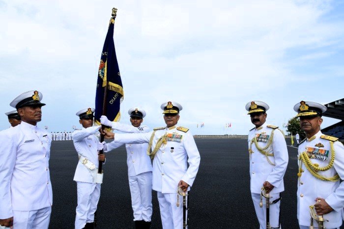 Merchant navy officer standing on deck wearing sailor's white uniform with ship background